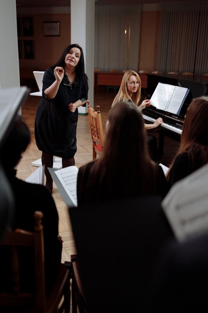 A choir rehearsal indoors with a conductor leading and a pianist accompanying.