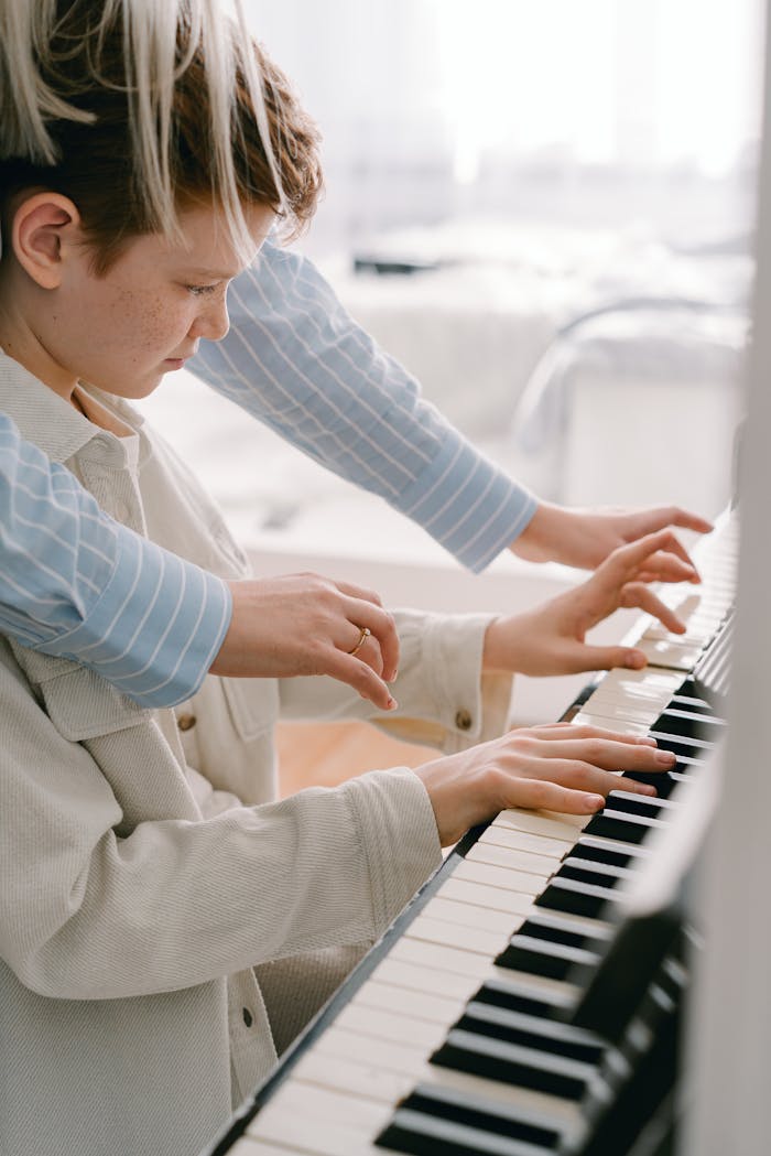 A student receives guidance from a teacher while learning to play the piano indoors.